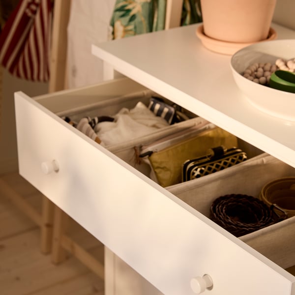 Close-up of HEMNES chest of drawers with the top drawer pulled out, to show the neat order inside with PURRPINGLA boxes.