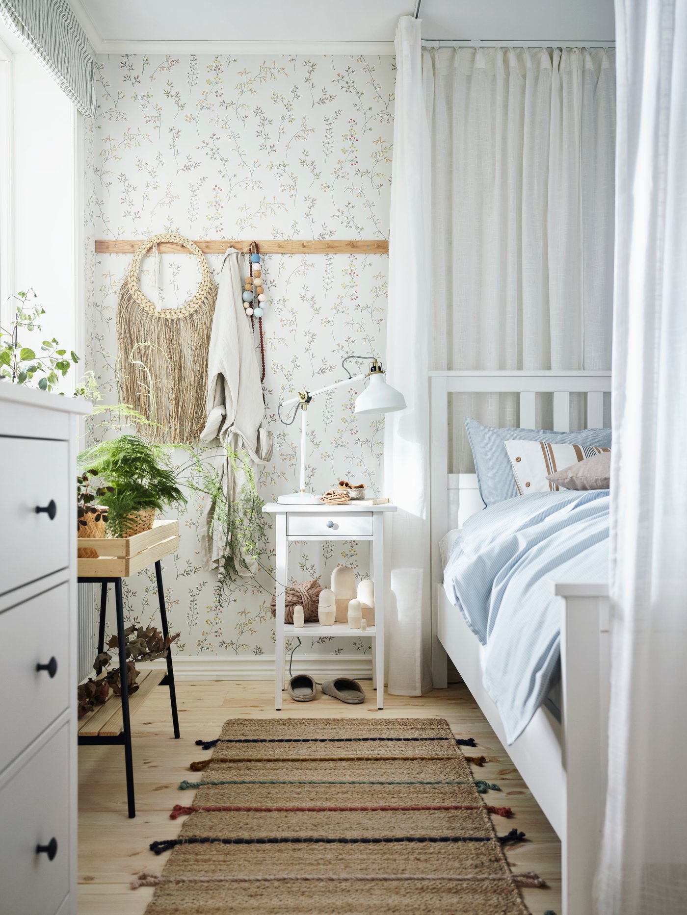 Et soveværelse med badehotelsteming med blomstret tapet og stribet sengetøj og puder.
