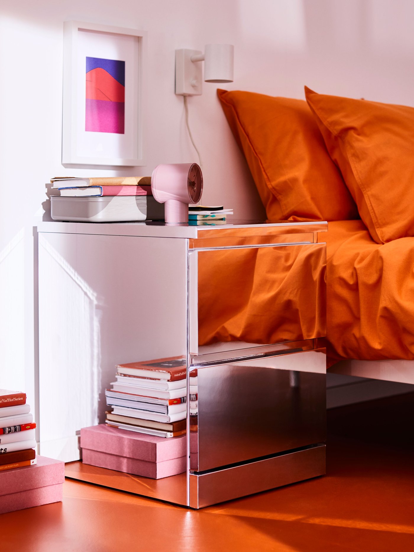 A white MALM storage bed opened showing storage items organized underneath the bed.