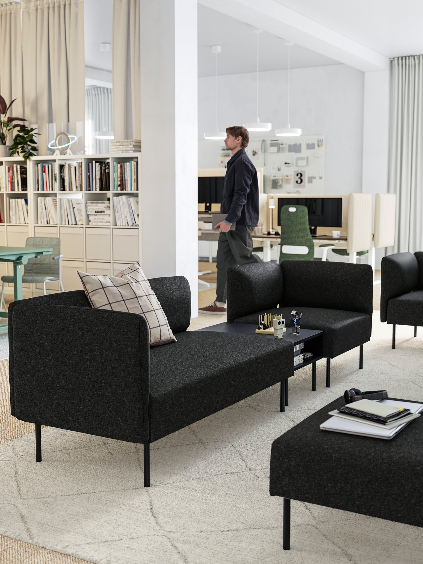 A relaxing lounge area with several LILLEHEM 2-seat and 1-seat sofa modules in dark grey, shown in a large white office.