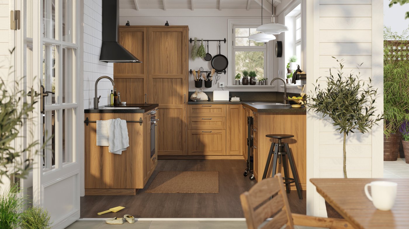 A sunny, white traditional-style kitchen with ENKÖPING brown walnut effect fronts and black mineral effect worktops.