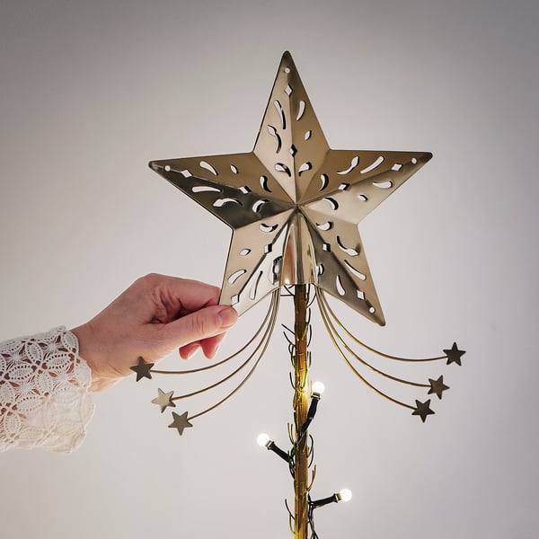 Hand placing a star-shaped tree topper on a decorated Christmas tree
