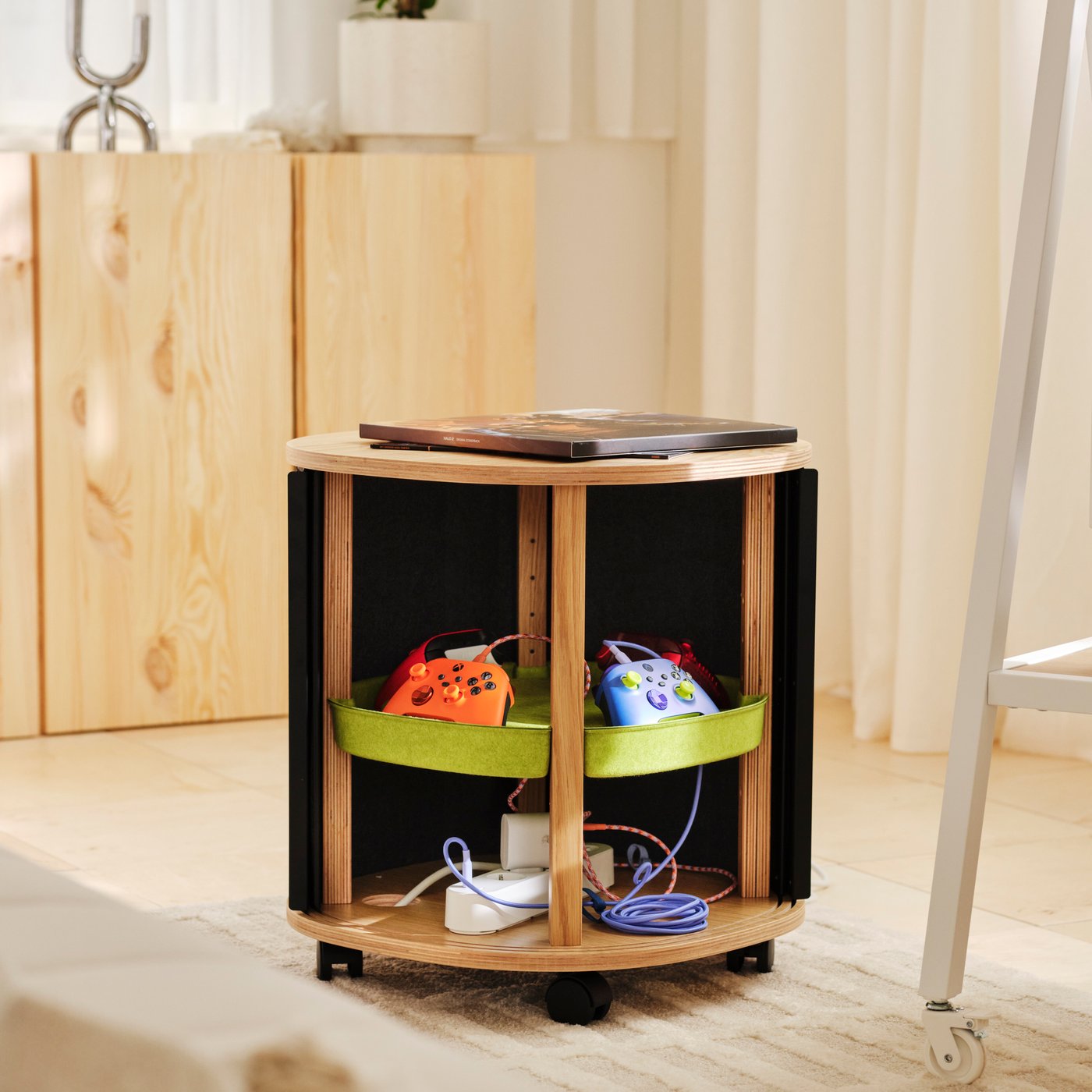 A YXSTABY side table with storage for controllers and other gaming essentials in a living room with wooden IVAR cabinets in the background.