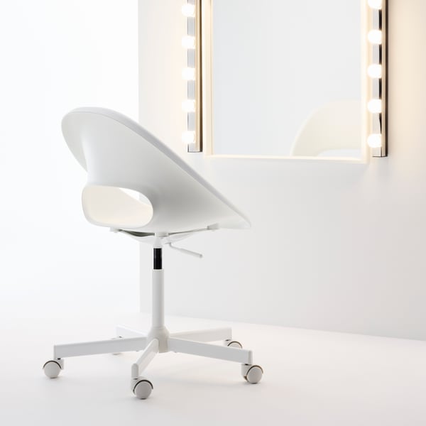 Une chaise pivotante LOBERGET blanche sur roulettes, vue de dos et placée devant un grand miroir de pièce-penderie avec éclairage.