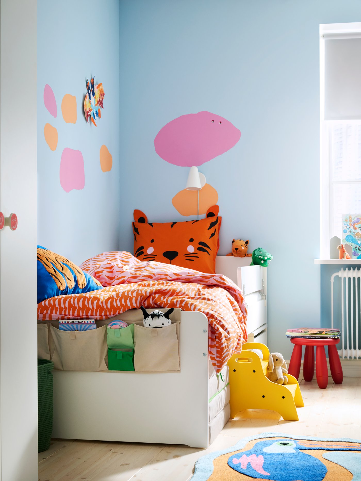 The corner of a children’s room with SLÄKT bed and NATTHÄGER bedding, two small stools by the bed, wardrobe in foreground.