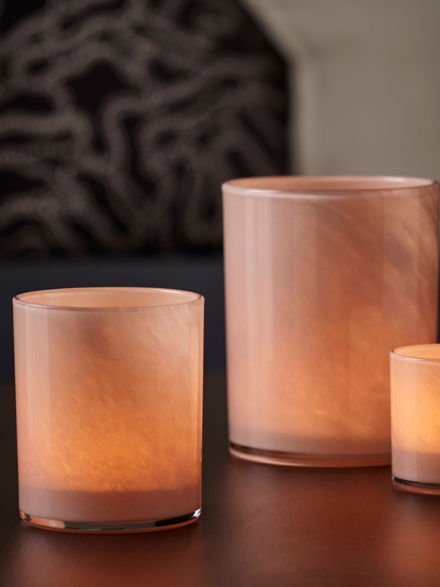Close upp on three candle holders in beige glass,