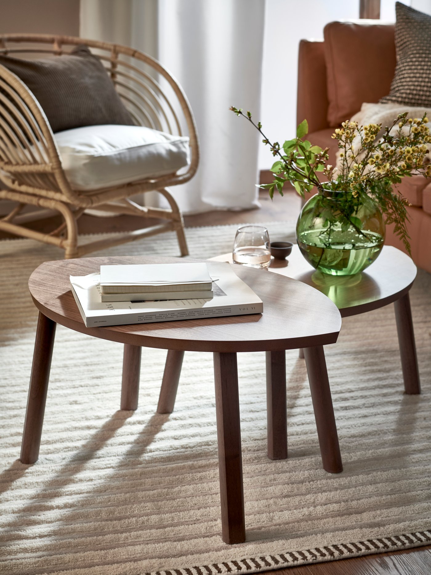 A set of two STOCKHOLM nest tables, with some books and a KONSTFULL vase with flowers on top, stands on a TÅGSPÅR rug.