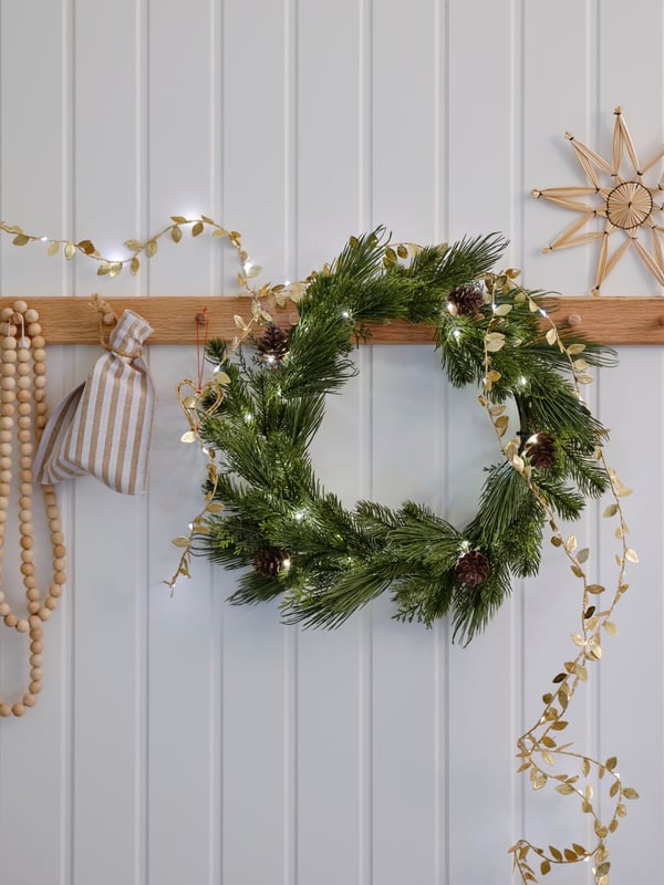 STRÅLA LED artificial garland and STRÅLA LED lighting chain in leaf gold-colour hang from HÖVOLM rack with 6 knobs in oak.