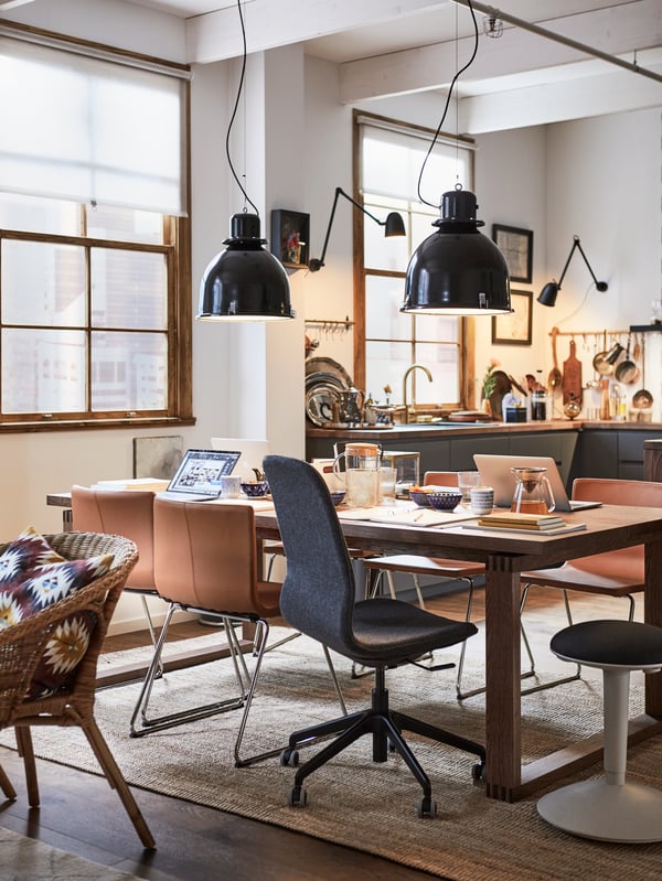 Dining room with pendant lamps, a MÖRBYLÅNGA table in brown stained oak veneer, with a mix of desk and dining chairs.