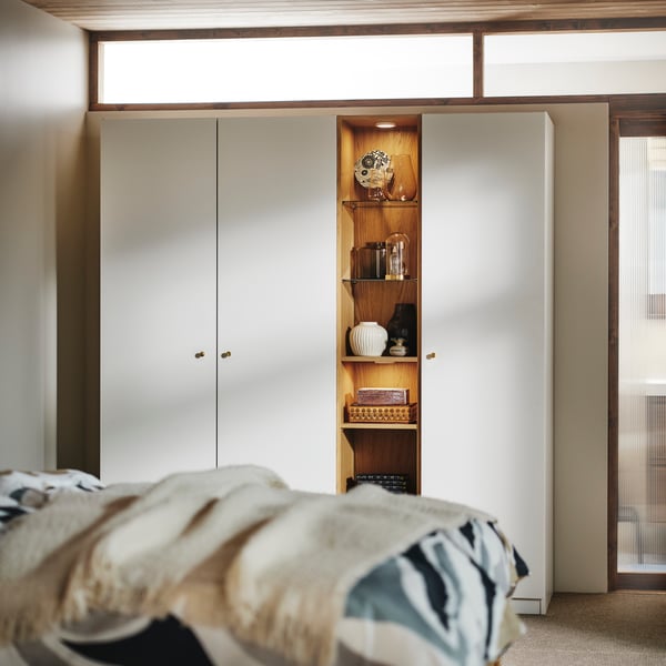 A white PAX wardrobe with a PAX mid unit between the two units. A mix of vases and collectibles on the shelves.