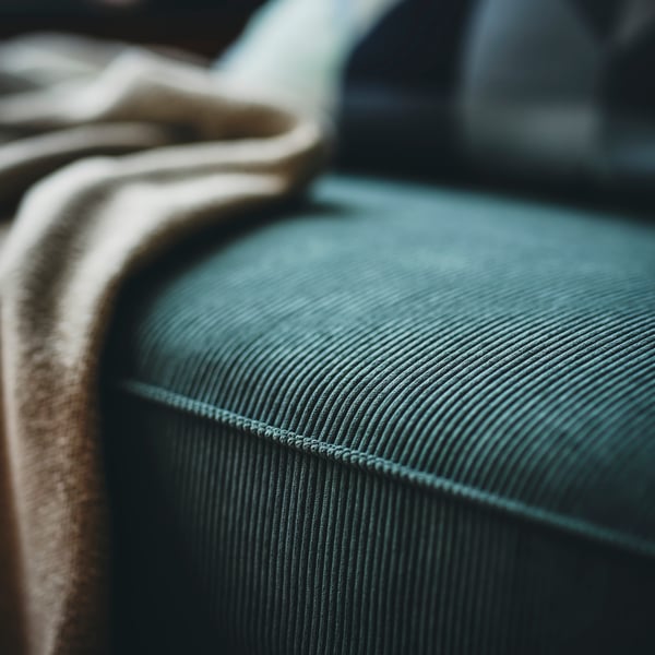 A close-up of a dark green VIMLE 2-seat sofa and a beige blanket.