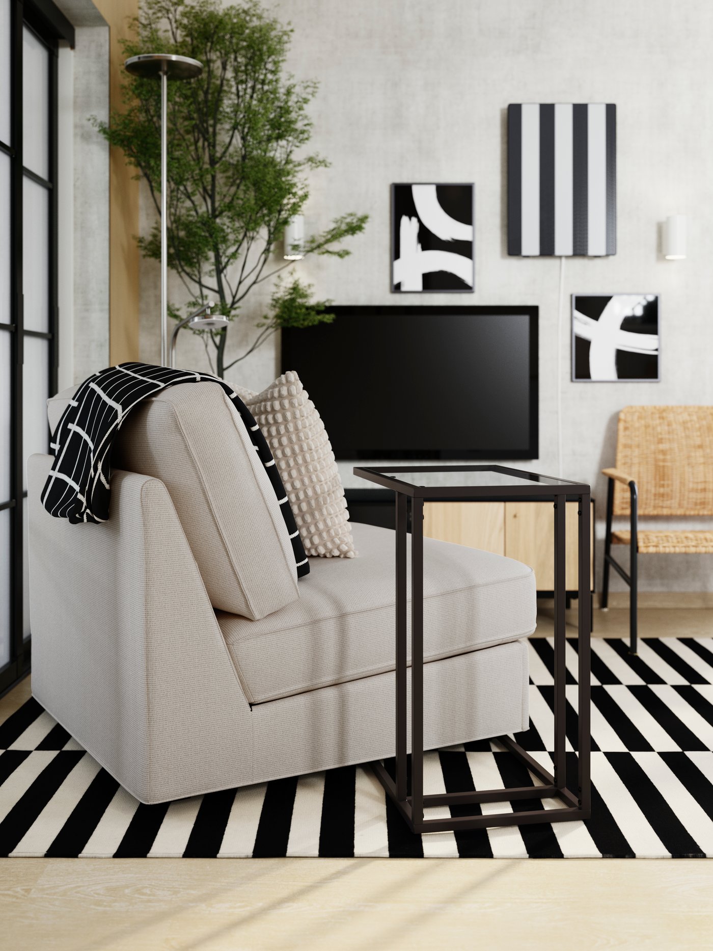 A light beige KIVIK 1-seat sofa-bed is angled on a black-and-white striped rug, facing a TV, and has a laptop stand by it.