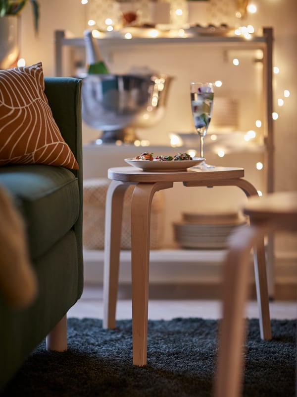 En KYRRE taburet med et champagneglas og en tallerken med snacks på. 