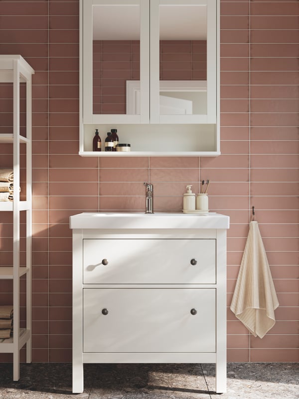 Un baño con paredes rosas y mueblesmodulares de baño de la serie HEMNES.