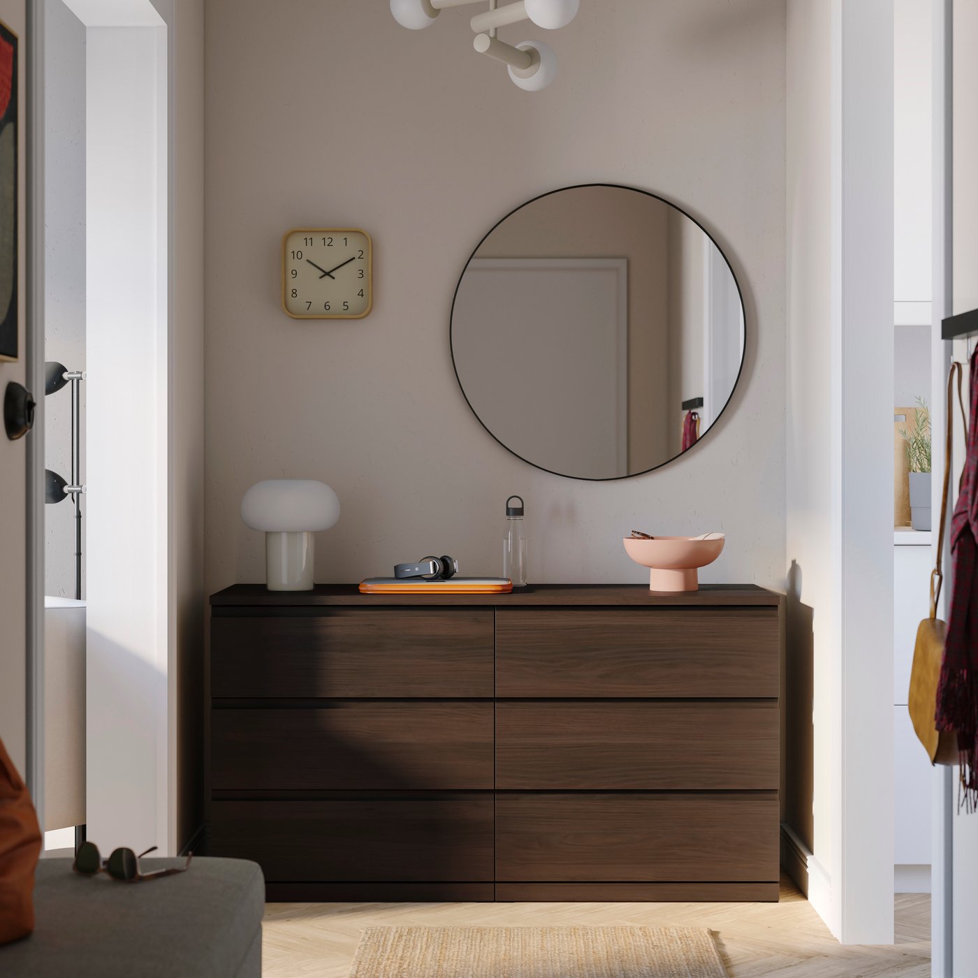 Dark wood dresser with a round wall mirror, clock, and decorative items in a modern entryway.