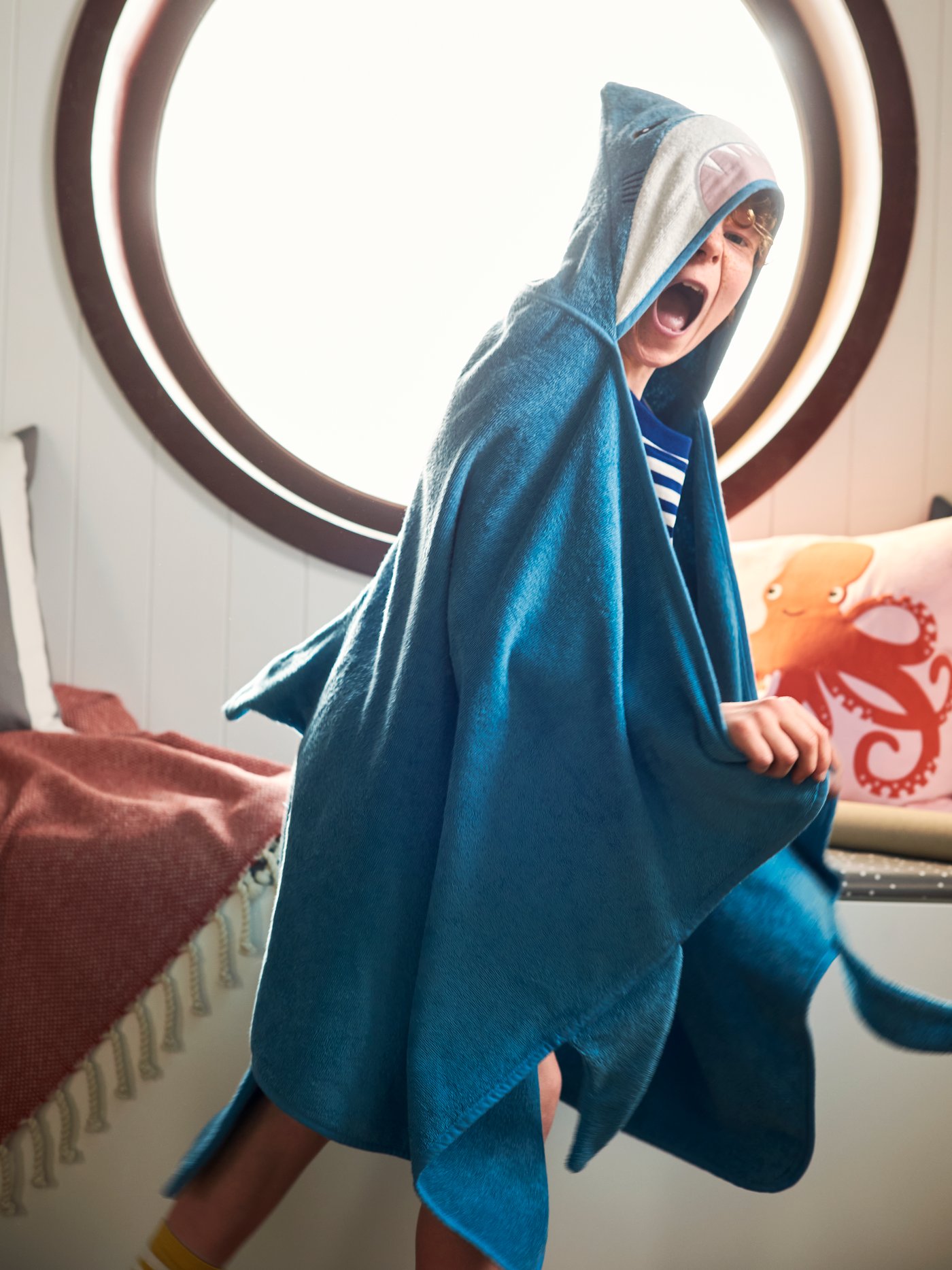 Un niño envuelto en una toalla BLÅVINGAD azul.