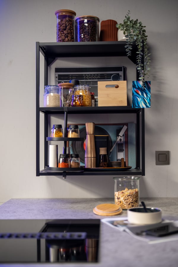 Een open IKEA wandkast met planken en glazen potten, gecombineerd met KORKEN voorraadpotten en keukengerei, zorgt voor een praktische en stijlvolle opbergoplossing.