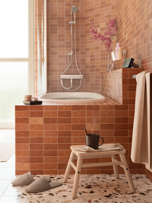 A bathroom with a BROGRUND thermo bath/shower mix, chrome plated, and a VILTO step stool in birch with a DINERA mug on it.