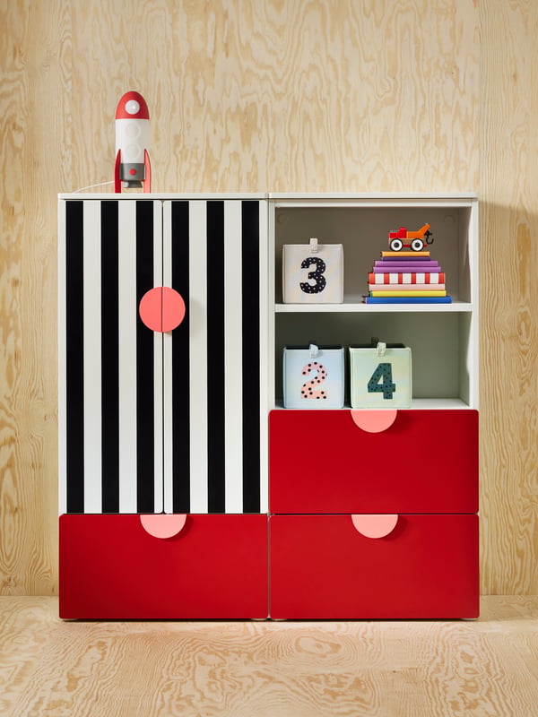 Red and black and white striped SMÅSTAD/PLATSA storage furniture for kids in a space with wooden walls and floors.