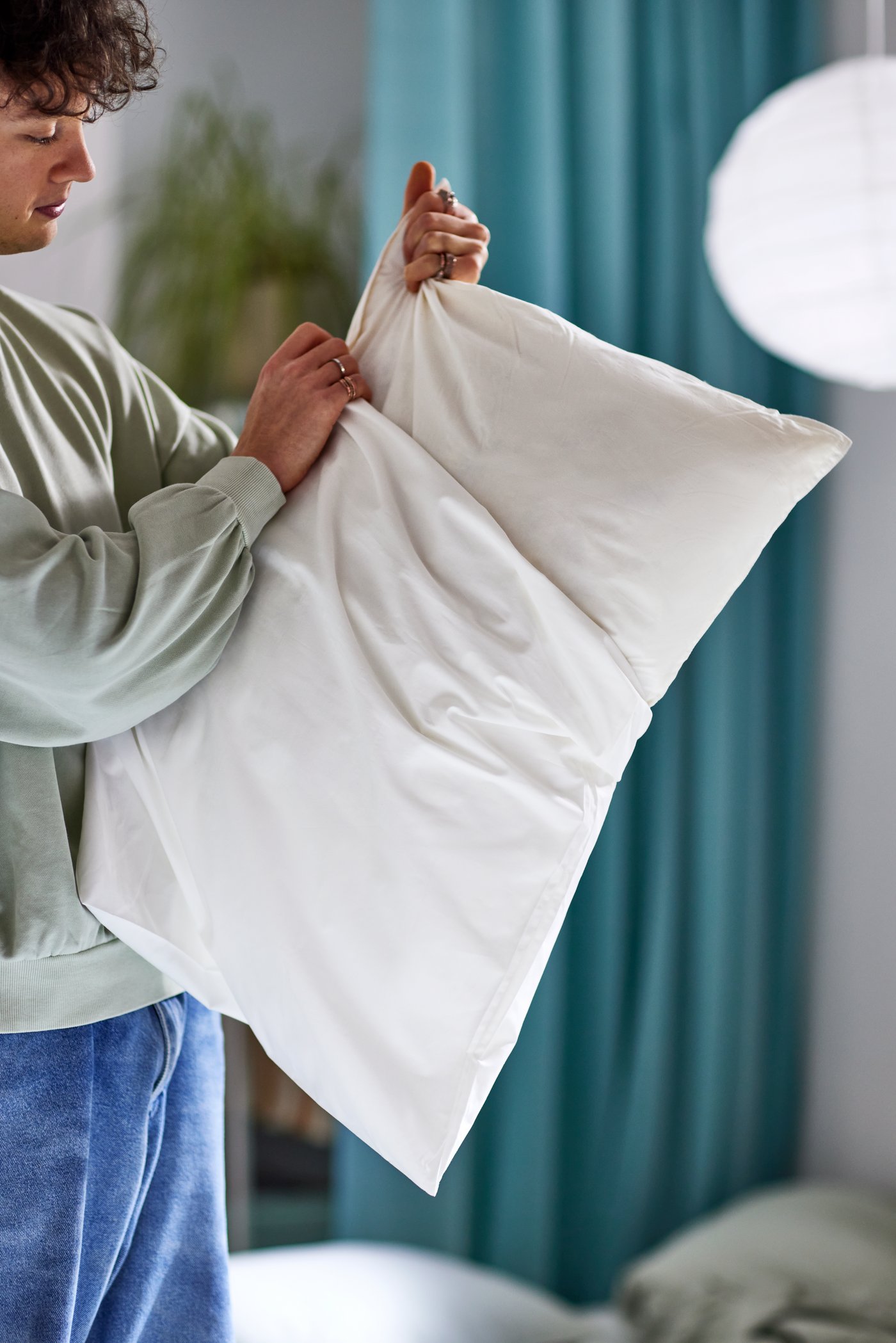 A boy lifts a white VILDKORN low cushion in a room - IKEA