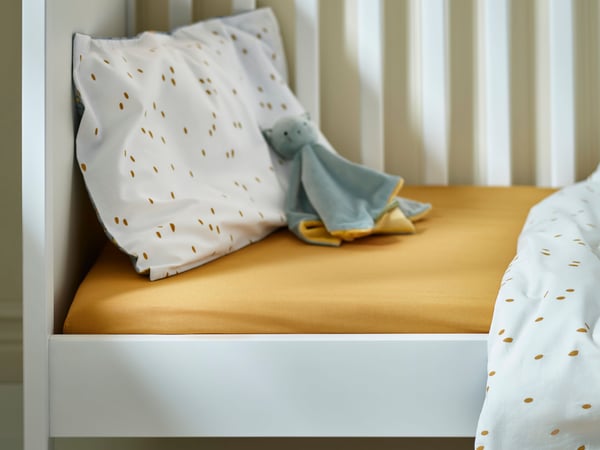 Une couverture douillette GULDVÄVARE bleue et jaune avec un doudou.