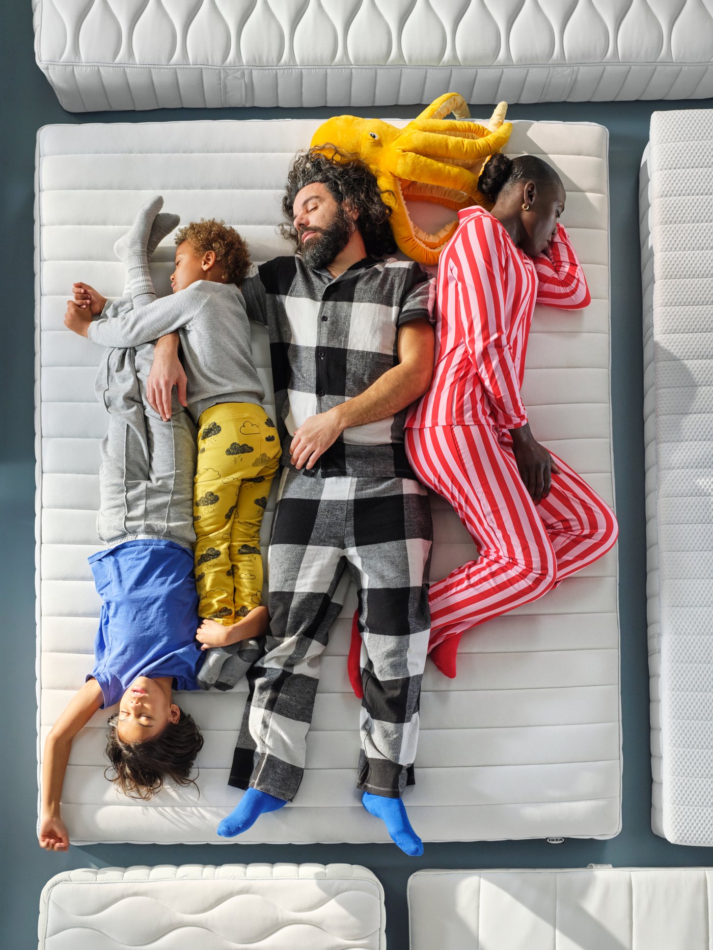 Gros plan d’une famille de quatre personnes en pyjama qui teste le confort d’un matelas VALEGÅG de IKEA.