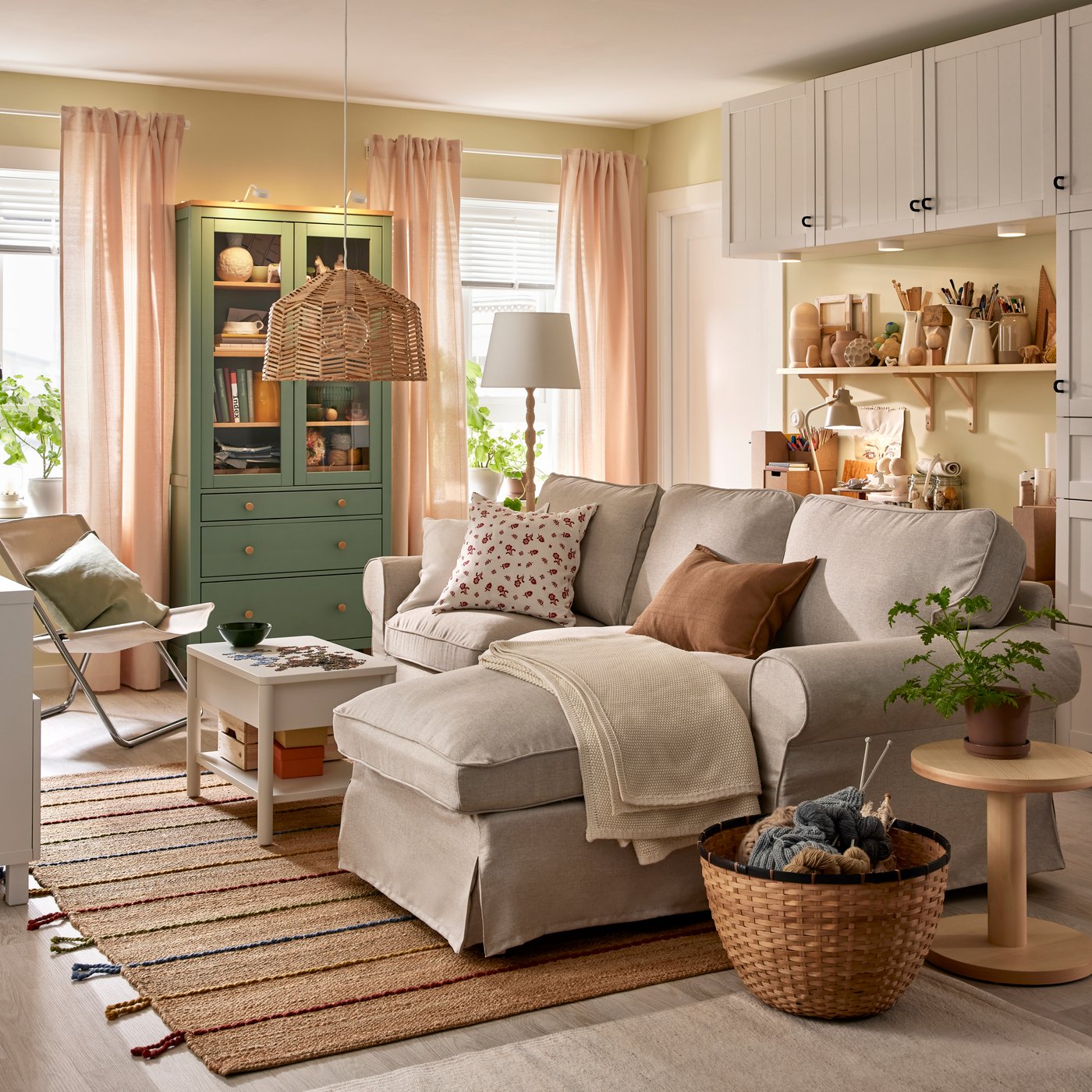 An EKTORP sofa with chaise longue stands in a functional living room near a HEMNES glass-door cabinet and some BESTÅ storage.