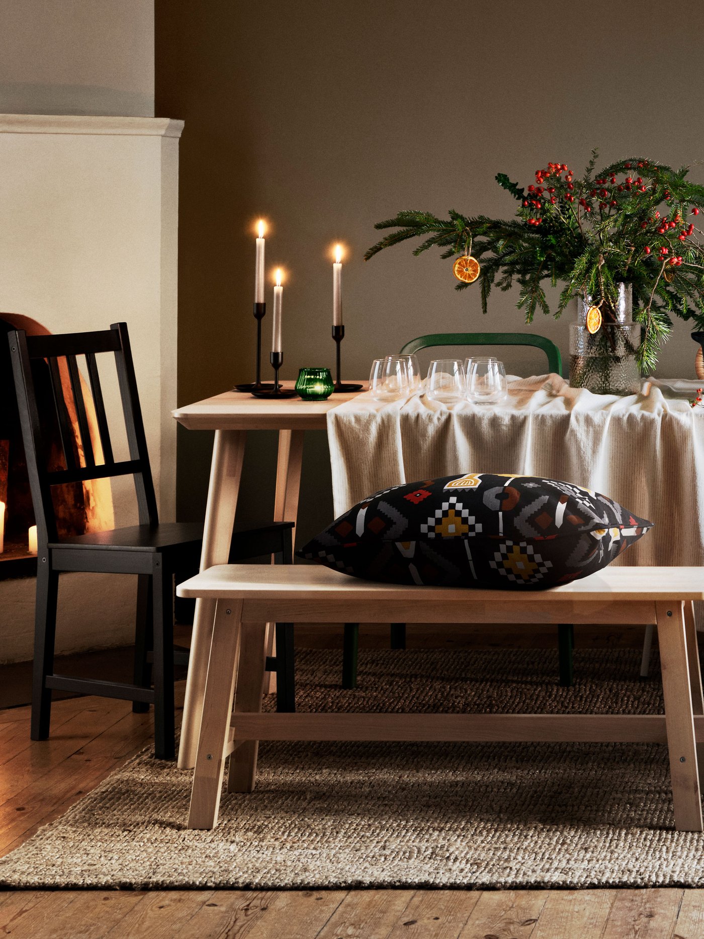 En kudde ligger på en bänk framför ett dukat bord.