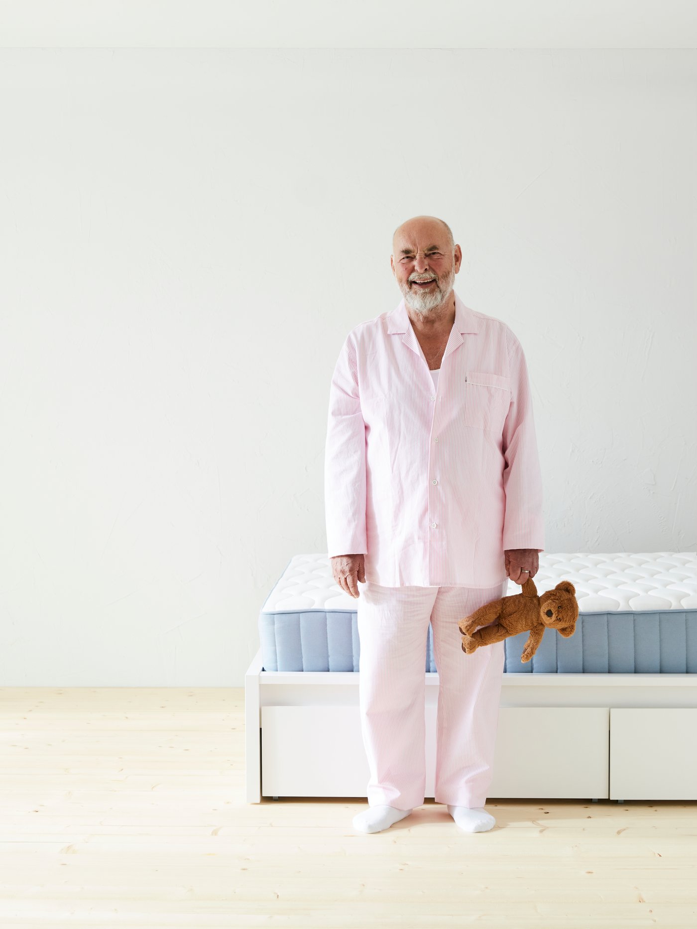 A man holding a bear BRUNBJÖRN soft toy in the bedroom