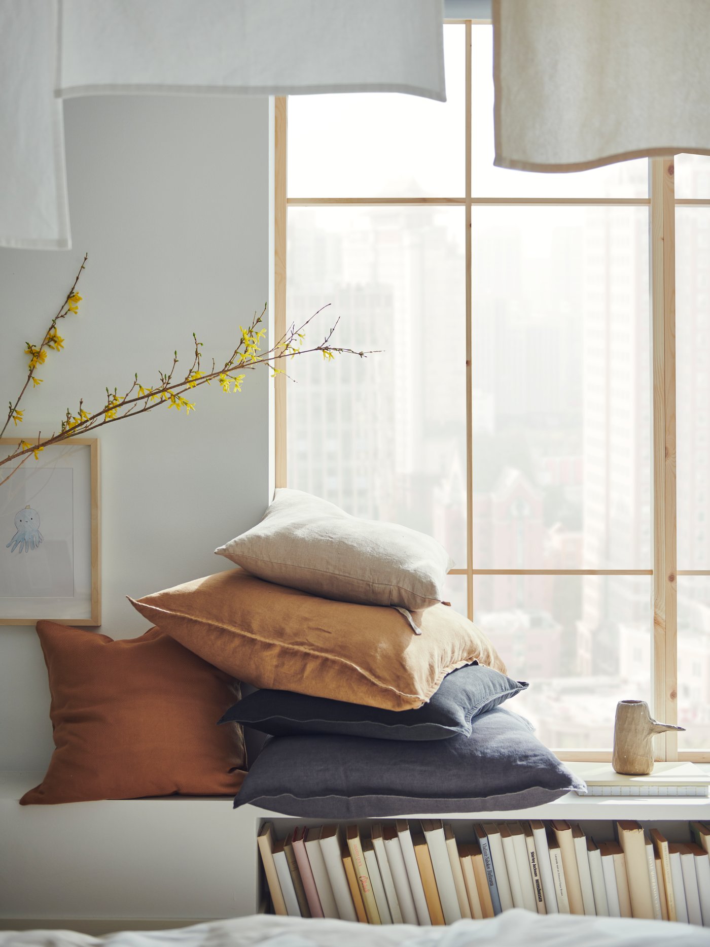 Cushions in different cushion covers including one in a dark beige DYTÅG cushion cover lie on top of a storage unit.