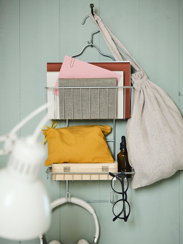 Pocinkovan KROKFJORDEN držač za tuš na zidu sa zelenim drvenim panelima na kom su knjige, naočare i razni drugi predmeti.