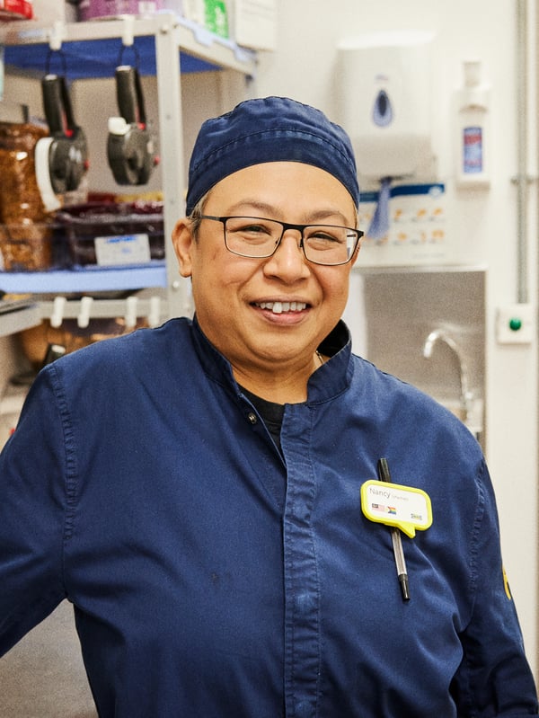 작업 유니폼을 입고 자신이 일하는 IKEA 푸드 주방에 서 있는 낸시의 모습.