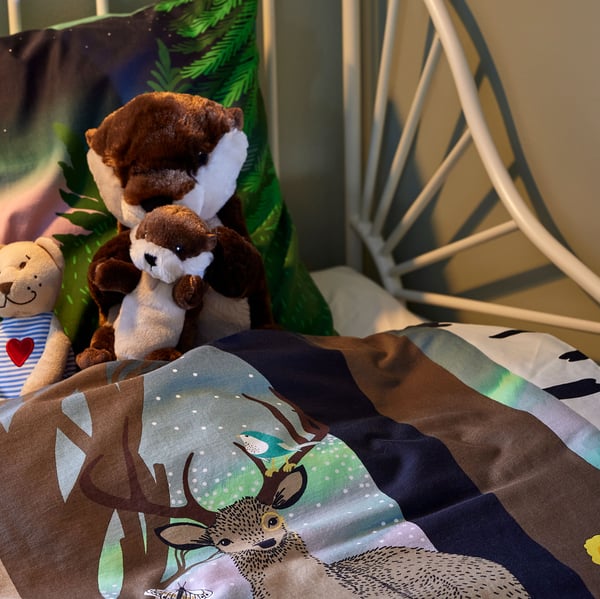 A children’s room with BUSUNGE extendable bed, SKOGSDUVA bedding and big soft toys in the bed.