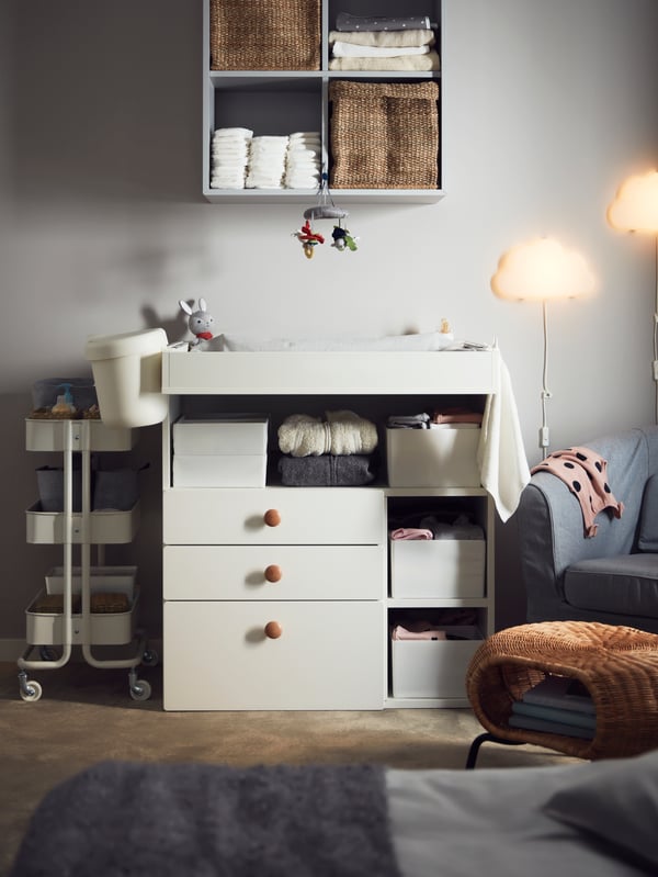 Una habitación con un mudador SMÅSTAD con cajones y artículos de limpieza organizados en sus cajones.