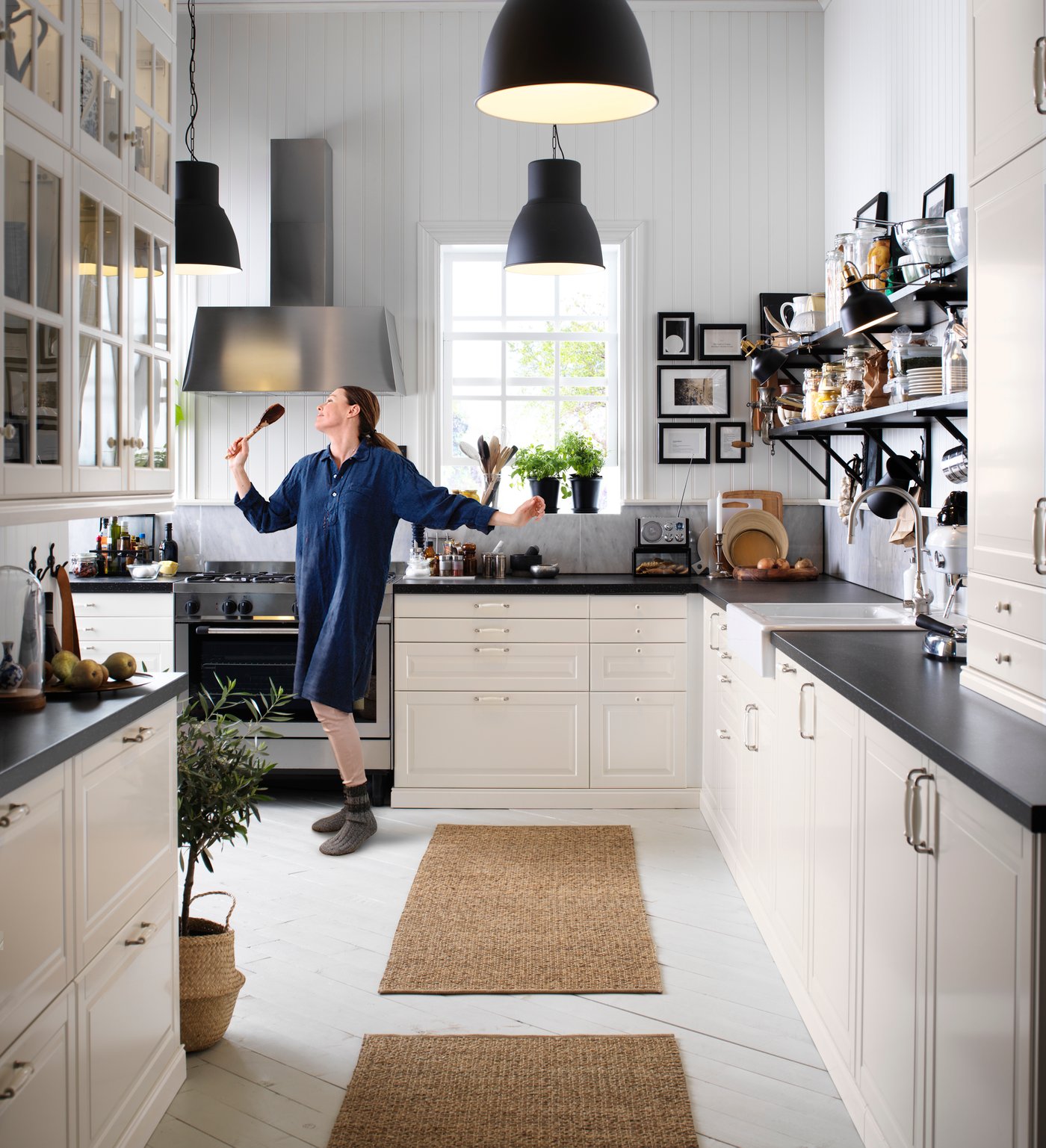 Helle Küche im modernen Landhausstil mit weißen Fronten und schwarzen Arbeitsplatten. Zwei rechteckige Küchenläufer liegen vor der Arbeitsfläche und sorgen für Komfort beim Kochen.