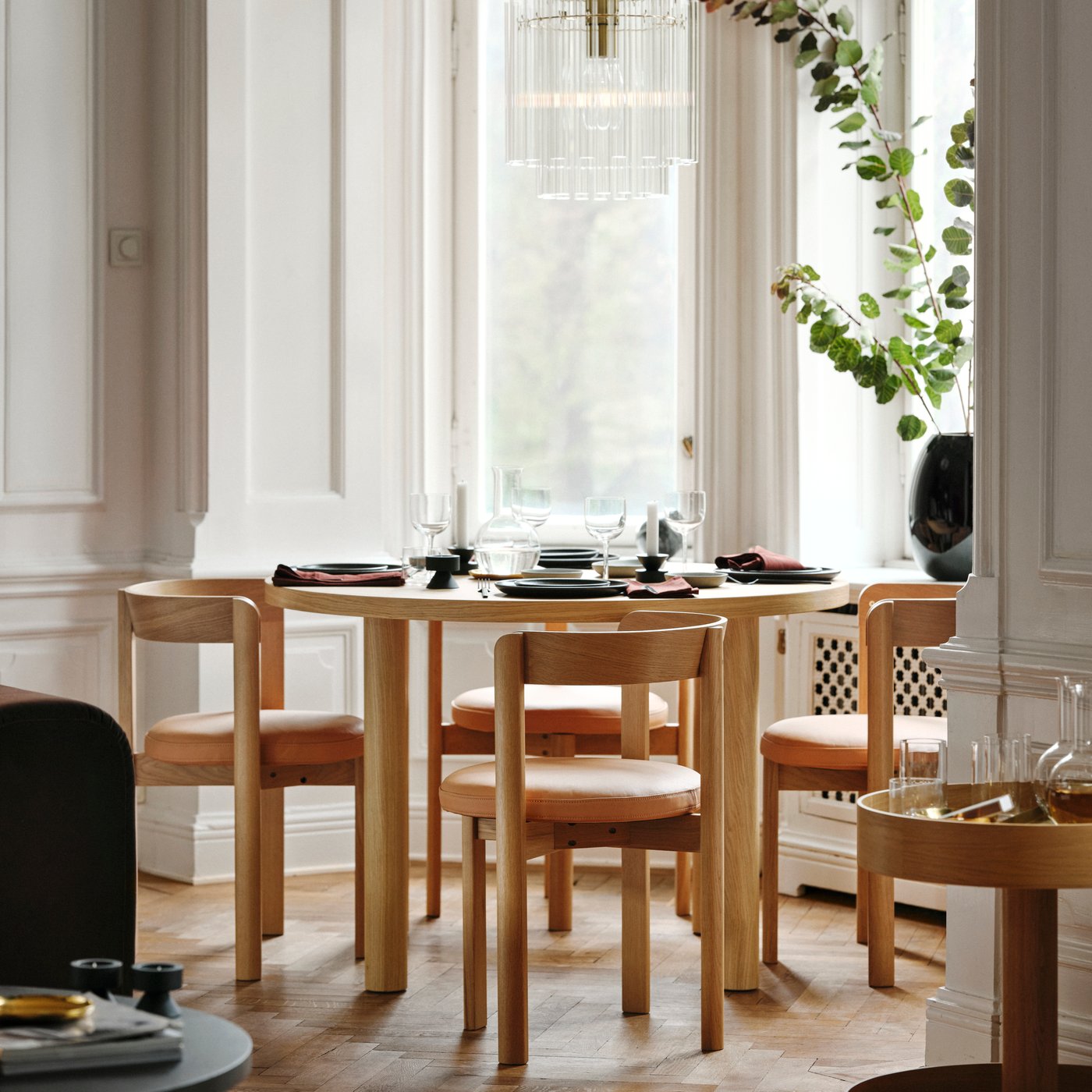 Ett STOCKHOLM 2025 bord vid ett fönster med stolar i läderimitationssits.