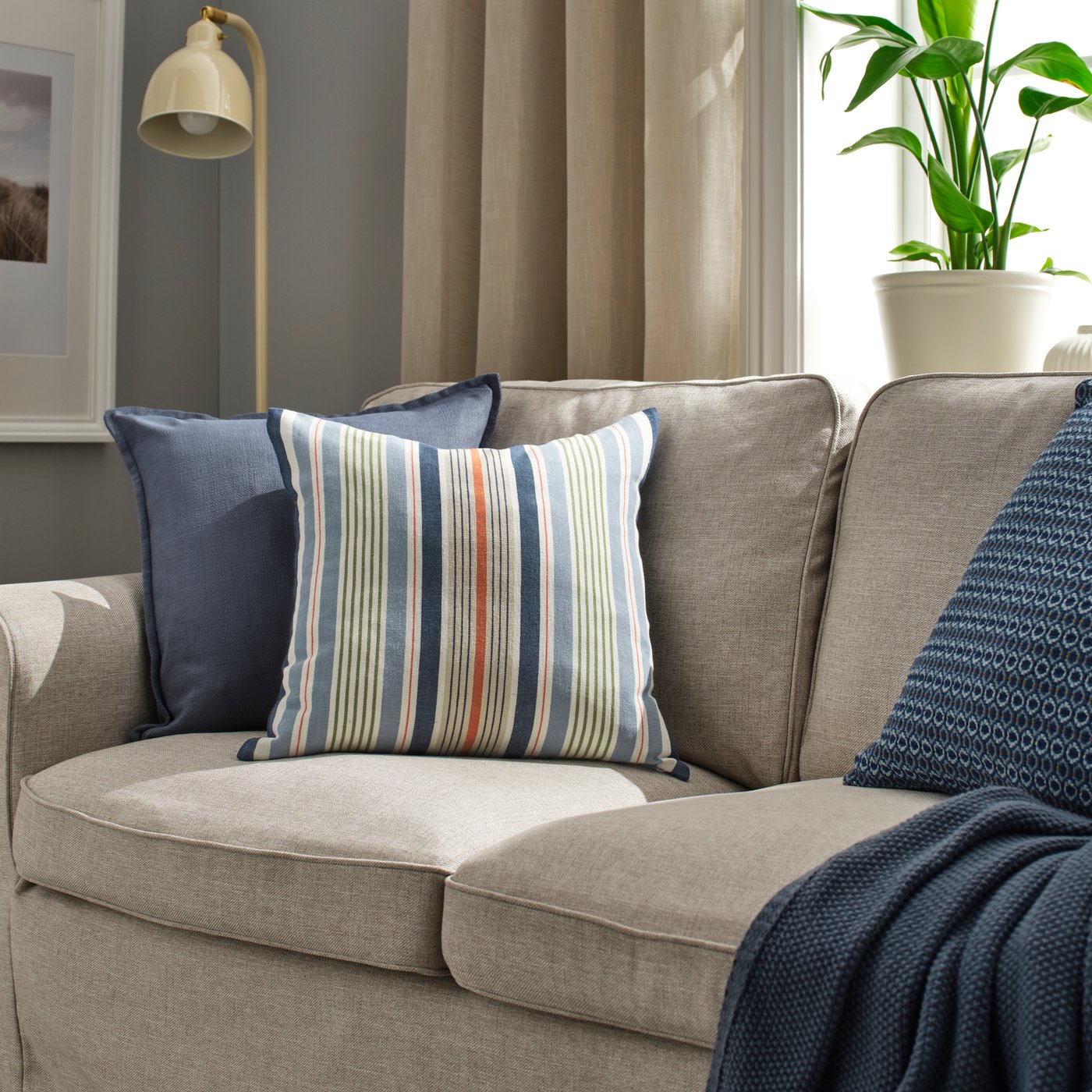 Multi striped toss pillow on a tan sofa