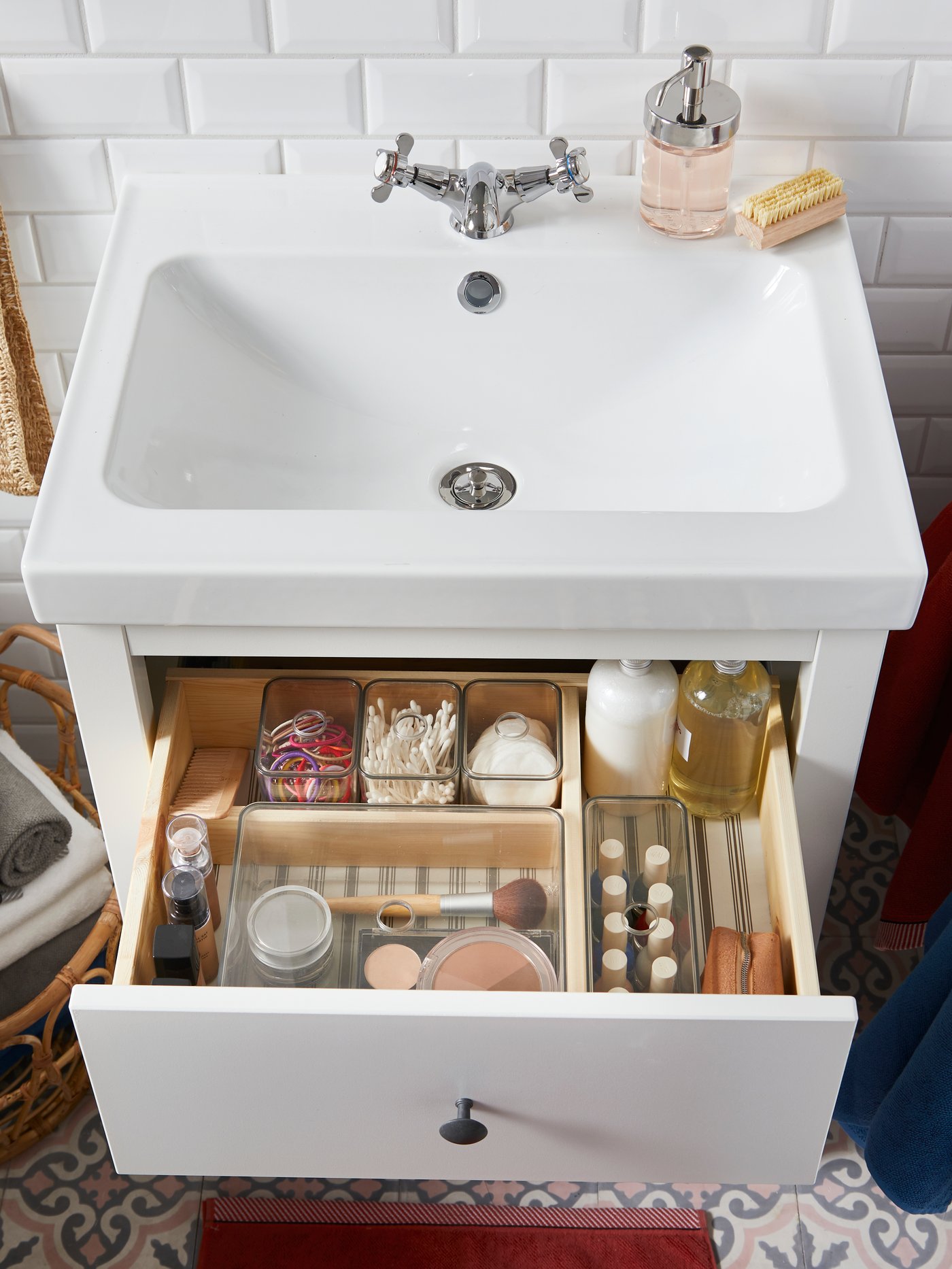 A white wash-stand with an open drawer containing smoked GODMORGON boxes containing beauty products and accessories.