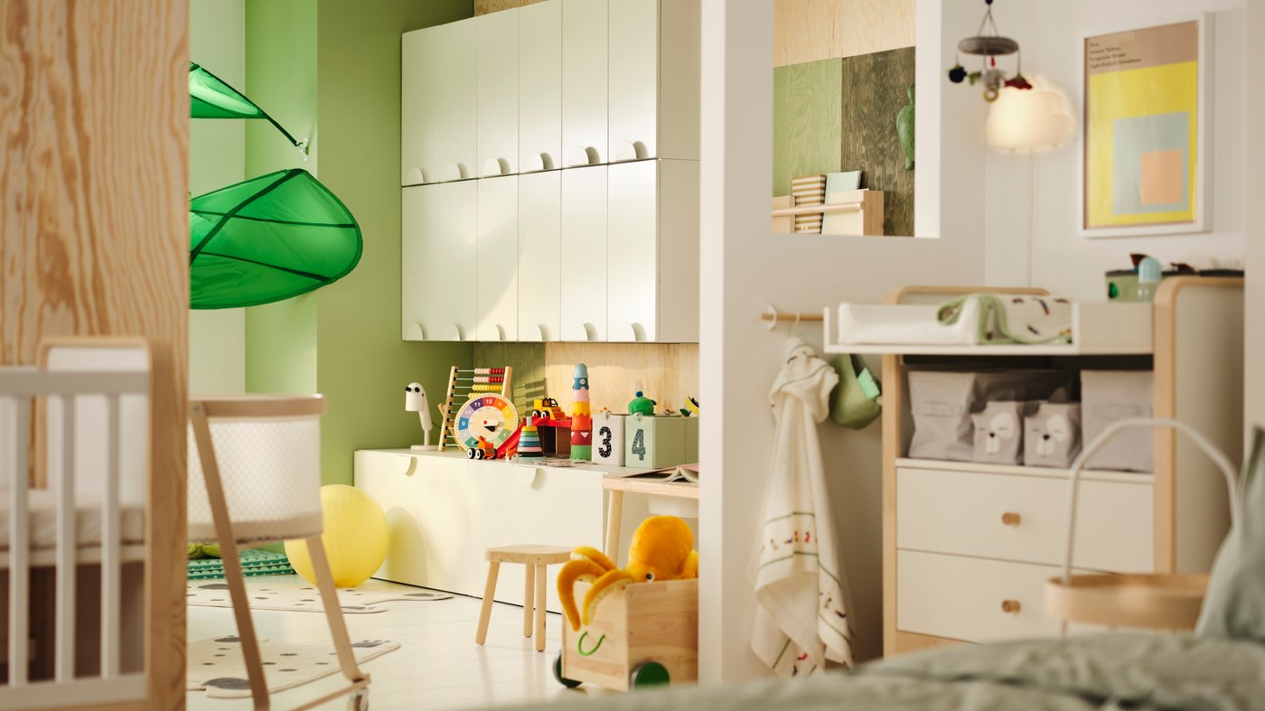 Es ist ein Kinderzimmer mit einer eingezogenen Trennwand zu sehen. Auf einer Seite stehen SMÅSTAD Schränke mit Spielzeug. Auf der anderen befindet sich ein Wickelbereich.