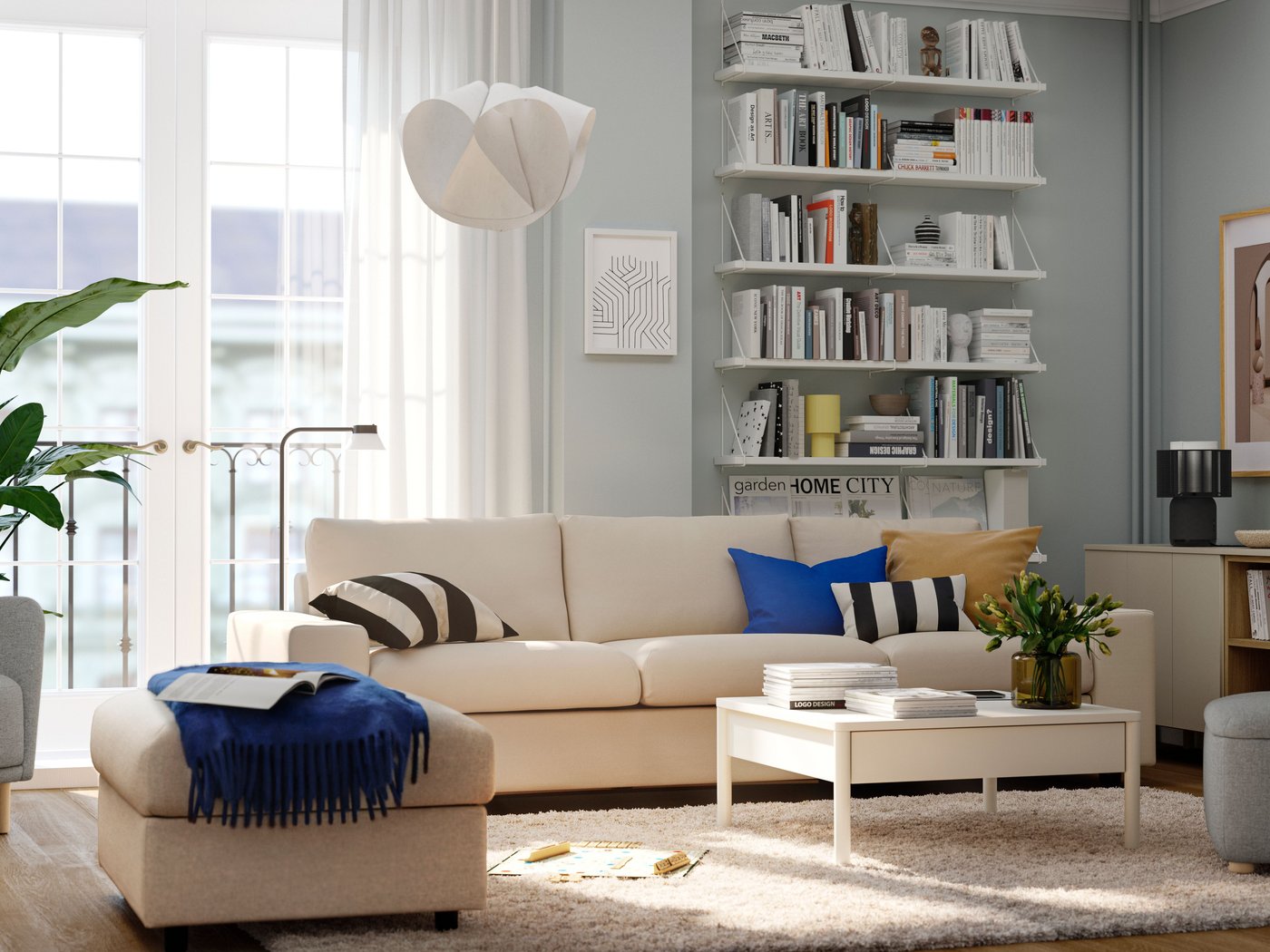 En rummelig og lys stue med en beige VIMLE sofa, et TONSTAD sofabord, farverige hynder og et blåt tæppe.