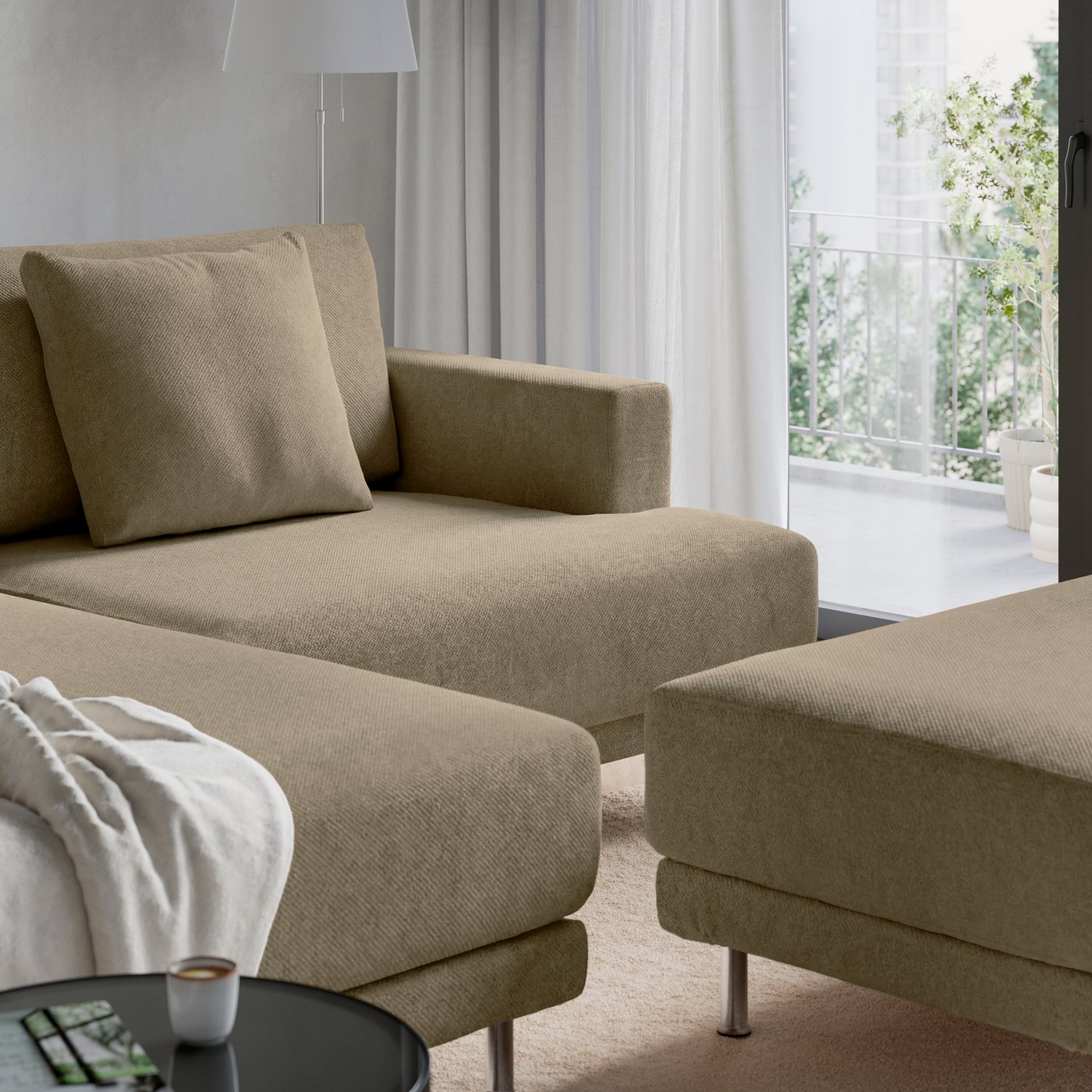 Närbild på en brunbeige UPPÅKRA soffa med schäslong och fotbpall stående vid stort fönster.