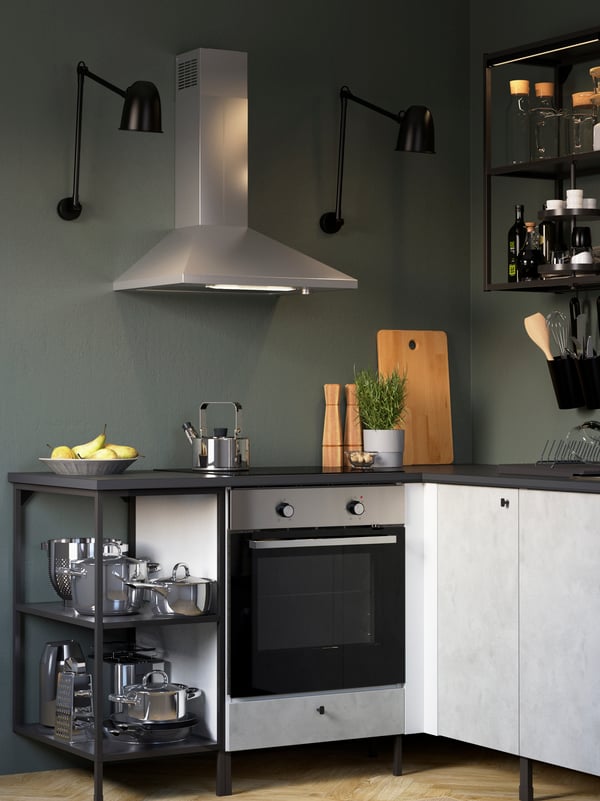 An ENHET kitchen with grey cabinets against a green wall with a wall-mounted extractor hood and two black wall lamps.