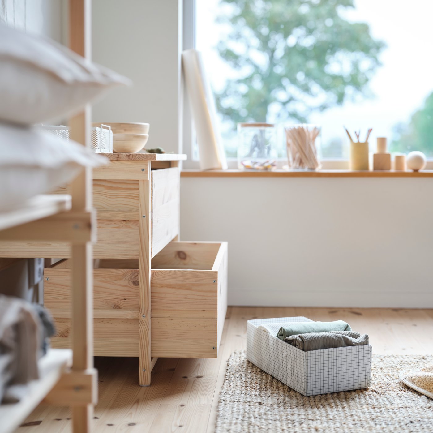 A STUK box with compartments lies on the floor of a bedroom in front of a KRONÖREN chest of 2 drawers.