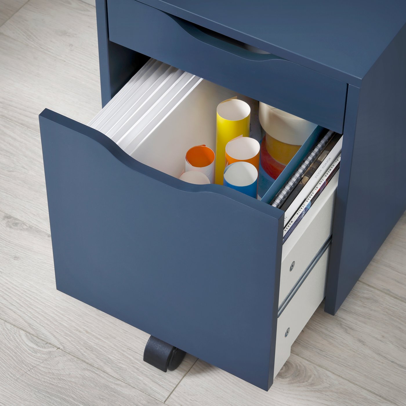 An opened drawer of a black-blue ALEX drawer unit on castors, showing different colours of paper rolls.