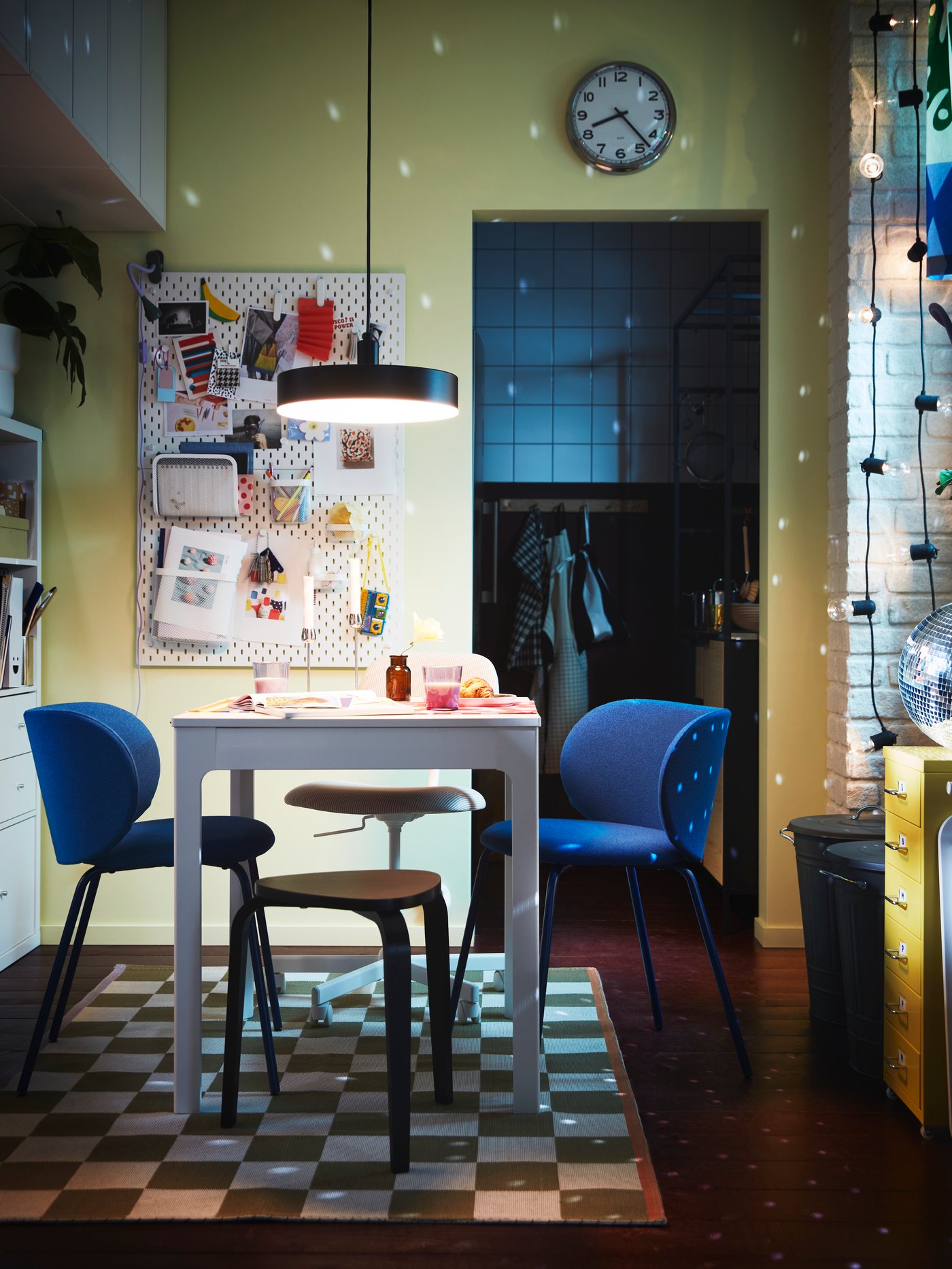 A disco ball sprinkles dots of light across a dim dining area with blue KRYLBO chairs around an EKEDALEN extendable table.