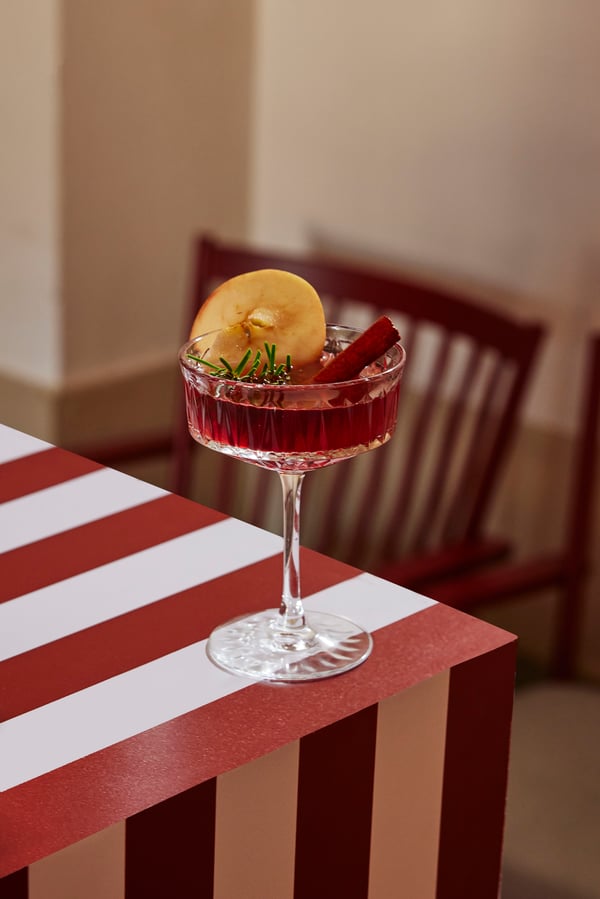 Ett fint champagneglas fyllt med glöggsangria dekorerat med apelsiskiva och kanelstång. 