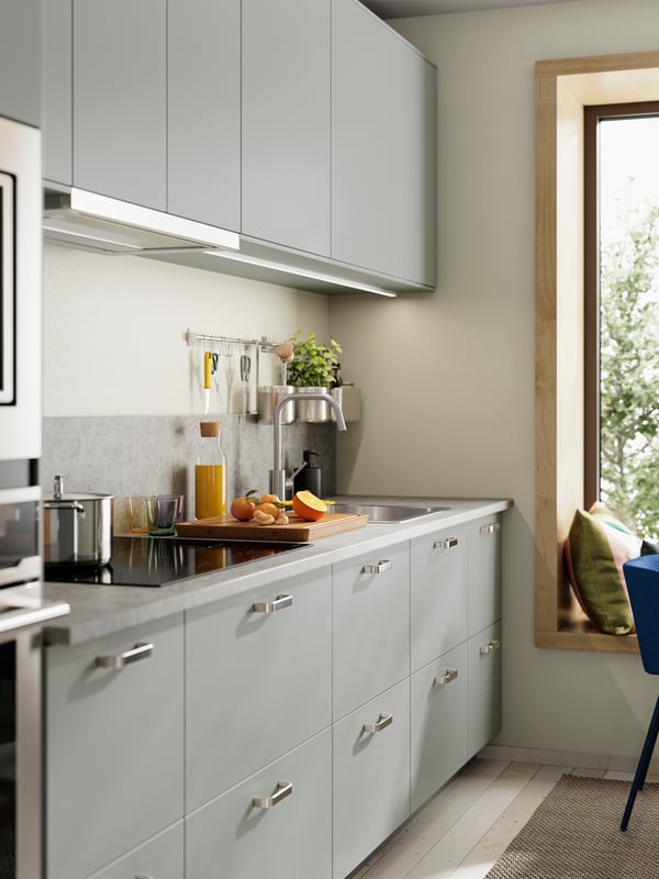 HAVSTORP light grey kitchen fronts paired with silver handles, a countertop with a cutting board, juice, and kitchen tools.