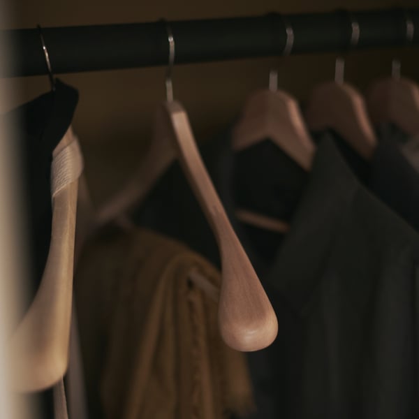 Five BUMERANG hangers on a clothes rail, with various items of clothing hanging from them.