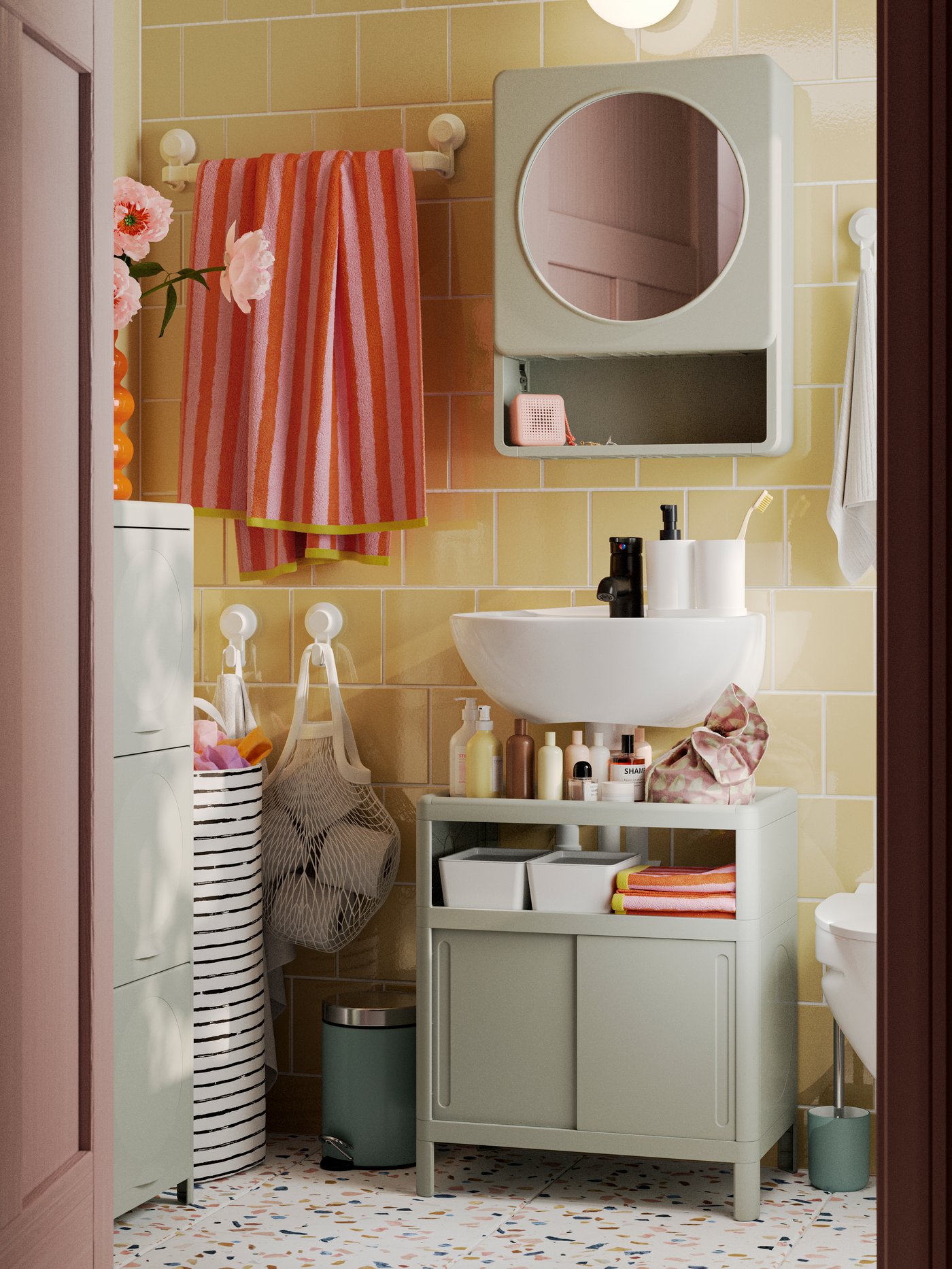 A green IVÖSJÖN wash-basin base cabinet, a mirror cabinet and a cabinet with doors are placed in a small yellow bathroom.