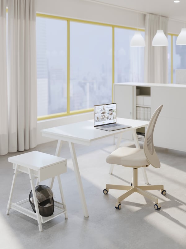 Un set de escritorio TROTTEN con silla con ruedas, cajonera y escritrorio, todo en blanco en una oficina amplia y luminosa